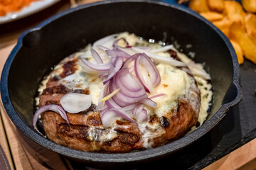 Onion Burger. Meat burger of ground meat fried in oil on a frying pan with three types of onions, close up