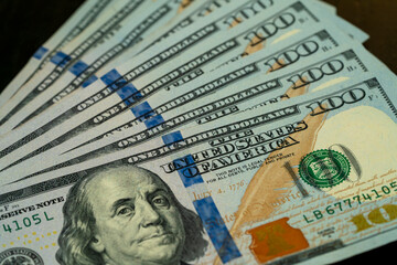 Stacks of hundred dollar bills arranged on a wooden surface