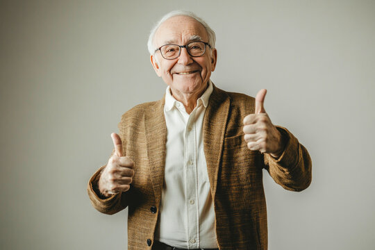 Elderly caucasian male showing thumbs up gesture with a smile in casual outfit