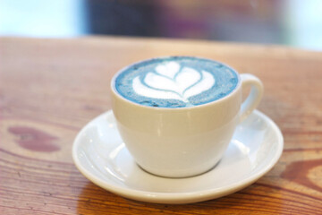 Blue matcha tea in a white mug on a table in a cafe