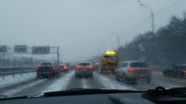 winter traffic jam, windshield or car window and blurry road lights, raining drops