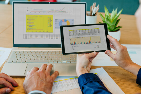 Colleagues comparing data on laptop and digital PC in office
