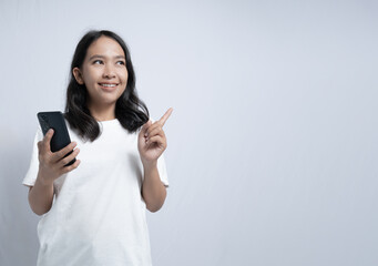 Fototapeta premium Smiling Woman Holding Phone and Pointing with White Background