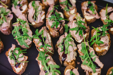 Gourmet bruschetta appetizers featuring slices of bread topped with meat, arugula