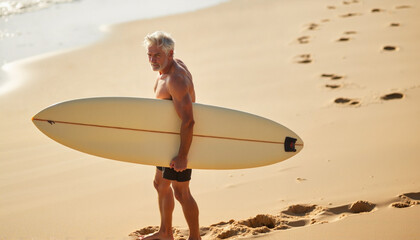 Seniors learning to surf Copy space active aging vacation Elderly man walking on beach carrying a surfboard.