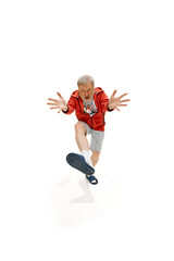 Senior man dressed red jacket, shorts and slippers dancing with joy raising hands against white studio background. Concept of business, occupation, human emotions and facial expressions. Ad