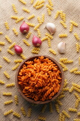 Spicy fried small macaroni crackers, on a brown cloth background, flat lay or top view, with studio lighting