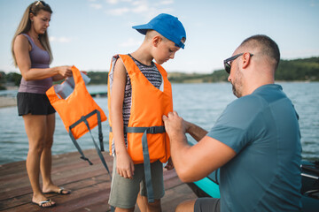 Father helping his son put on a life jacket before kayaking