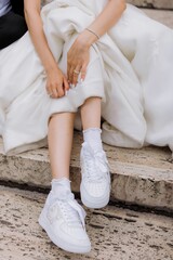 Bride in sneakers on stone steps