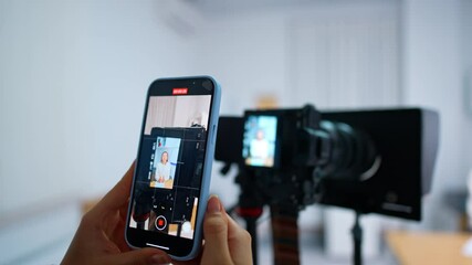 Recording display of a professional camera to a smartphone. Lady is taking video on her phone. Close up.