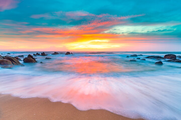 Dreamy dawn landscape on beautiful beach with waves crashing on the shore creating silk-like...
