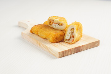 vegetables risoles enclosed in crepe-like wrappers and rolled into bread crumbs and fried. served on wood plate. perfect for recipe, article, catalogue, promotion, or any cooking contents.