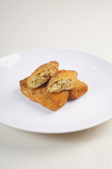 chicken rissoles enclosed in crepe-like wrappers and rolled into bread crumbs and fried. served on wood plate. perfect for recipe, article, catalogue, promotion, or any cooking contents.