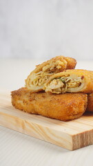 chicken rissoles enclosed in crepe-like wrappers and rolled into bread crumbs and fried. served on wood plate. perfect for recipe, article, catalogue, promotion, or any cooking contents.