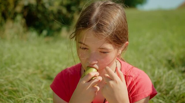 Young girl eating pear, biting into juicy fruit. Female enjoying fresh pear outdoors, savoring natural sweetness. Lady tasting ripe pear, appreciating its fresh flavor in sunny surroundings