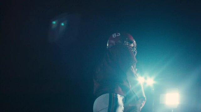 An American football player practicing throwing and catching the ball on a field