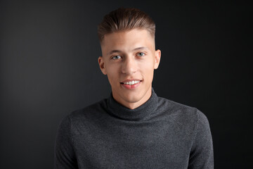 Handsome young man with stylish haircut on black background