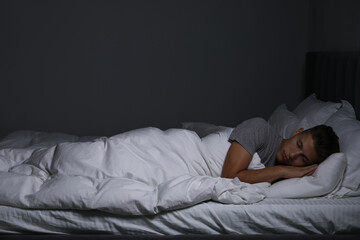 Young man sleeping in soft bed at night