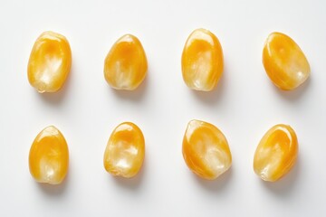 Close up of eight yellow corn kernels on a white surface