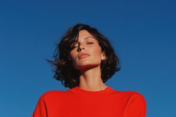 Fashion model posing with blue sky background, wearing red sweater