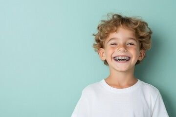 Portrait of smiling child showing braces on teeth on turquoise background