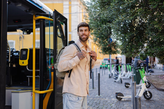 Young tourist getting off the bus in lisbon, portugal, with electric scooters parked on the street
