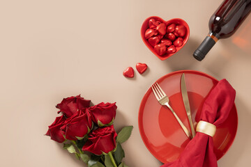 Valentine's day. Romantic dinner for date with red plate, chocolate sweets, romantic gift and red roses on beige background. Elegance table setting. View from above. Copy space.