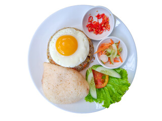 A plate of Nasi Goreng, Indonesian fried rice with a sunny-side-up egg, fresh veggies, crackers, pickles, and chili slices, served on a white over a white isolated background
