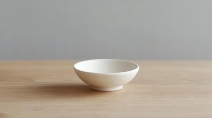 Minimalist White Ceramic Bowl on Wooden Table Against Soft Gray Background, Perfect for Food Styling and Interior Design Inspirations