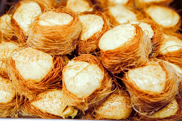 Delicate kanafeh nests, filled with creamy cheese and dusted with cinnamon, offer a delightful blend of textures and flavors, perfect for a sweet treat.