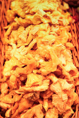 A pile of sweetened dried pineapple, vibrant and chewy, showcased in a rustic basket, perfect for a healthy snack or a flavorful addition to recipes.