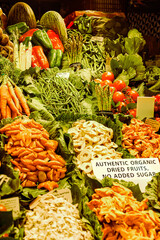 Lush display of fresh vegetables, including asparagus, carrots, cucumbers, and bell peppers, complemented by organic dried fruits, all vibrant and inviting at a local market.