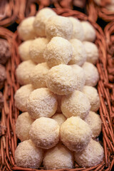 Delicate coconut truffles, artfully arranged in a woven basket, offering a soft, sweet bite with a lush, snowy texture, perfect for a festive treat.