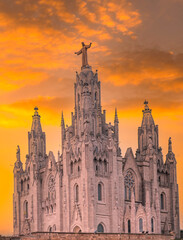 Fototapeta premium Expiatory Church of the Sacred Heart of Jesus, located on Mount Tibidabo in Barcelona, set against a dramatic orange sunset.