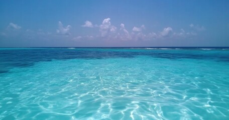 Fototapeta premium The ocean is calm and clear, with a few clouds in the sky