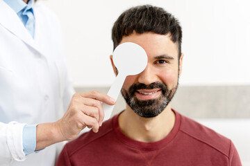 Doctor checking patient eyesight with occluder in medical clinic