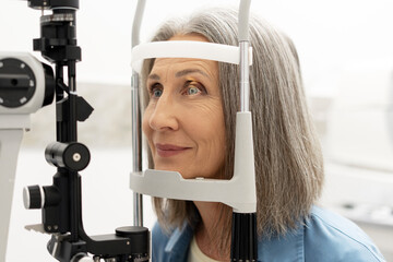 Senior woman undergoing eye exam with slit lamp: healthcare and vision care