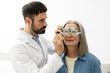 Optometrist examining senior woman with phoropter during eye exam