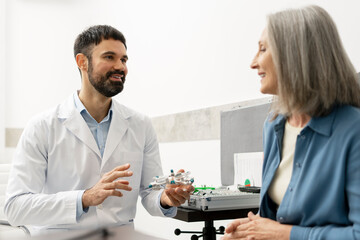 Optometrist showing eyeglasses to senior patient in ophthalmology clinic