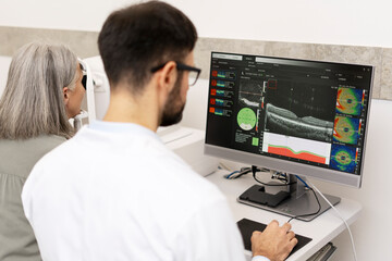 Ophthalmologist analyzing optical coherence tomography scan results on computer