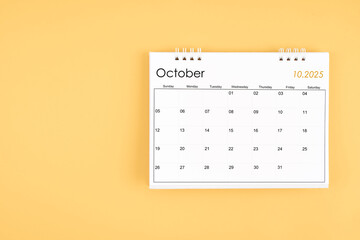 October 2025 desk calendar on yellow color background, position with copy space.