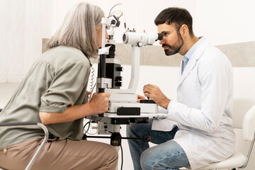 Senior woman undergoing eye exam with optometrist using slit lamp