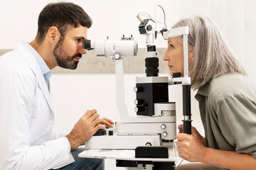 Ophthalmologist examining senior woman with slit lamp in clinic