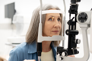 Senior woman undergoing eye examination with slit lamp biomicroscope