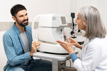 Ophthalmologist explaining autorefractor device to patient during eye exam