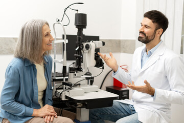 Senior woman undergoing eye exam with optometrist explaining test results