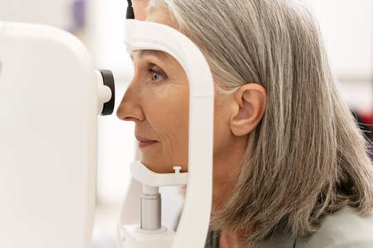 Senior woman undergoing eye exam with modern equipment