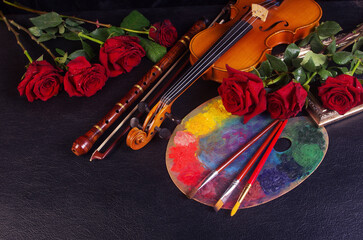 Music and painting, attributes of the arts. Violin, bow, pipe, art palette, brushes, red roses on a...