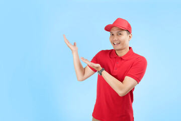 An Asian courier in a bright red uniform gestures confidently on a blue background. He highlights efficiency and commitment to fast delivery service.