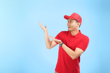 An Asian courier in a red uniform points enthusiastically to the side on a blue background. He conveys excitement and confidence in delivering reliable service.